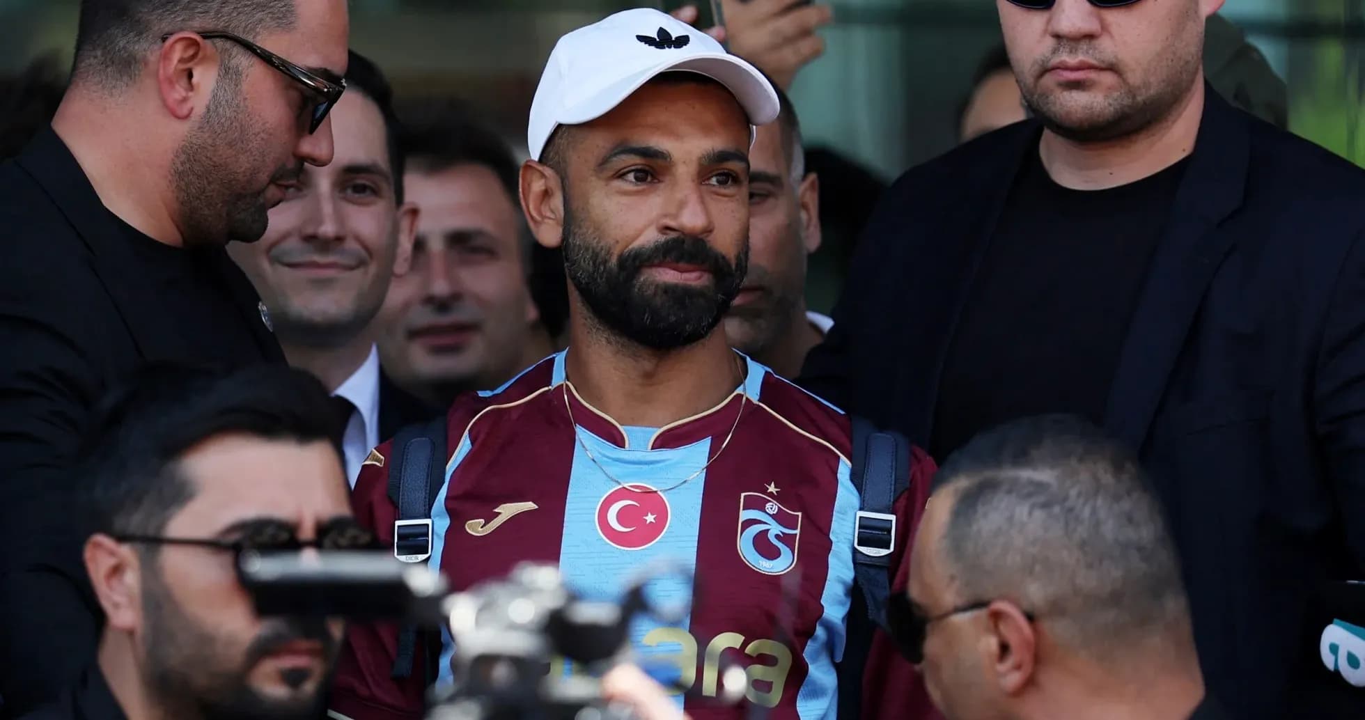 Player arriving surrounded by security personnel Player arriving surrounded by security personnel