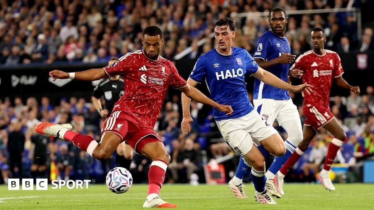 Liverpool player kicking ball past opposing defender Liverpool player kicking ball past opposing defender