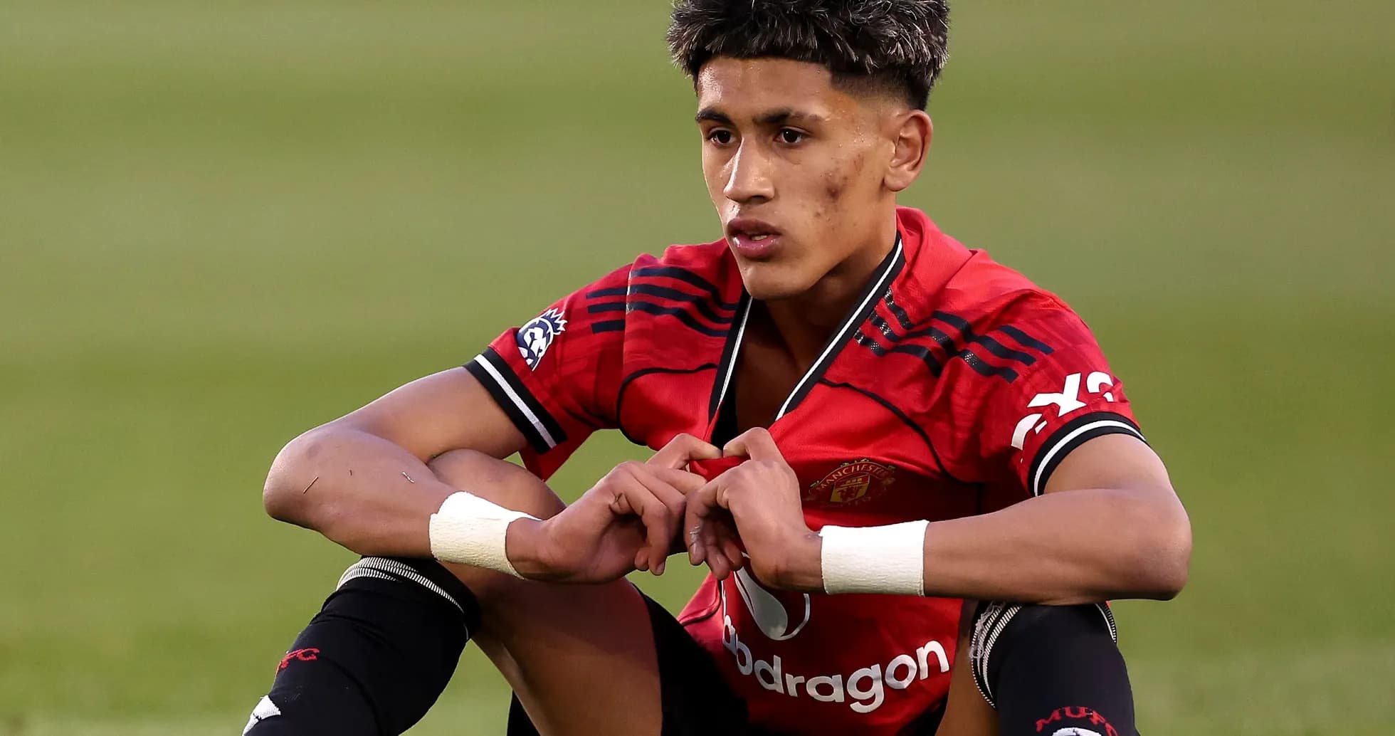 Young player sitting on field in Manchester United kit Young player sitting on field in Manchester United kit