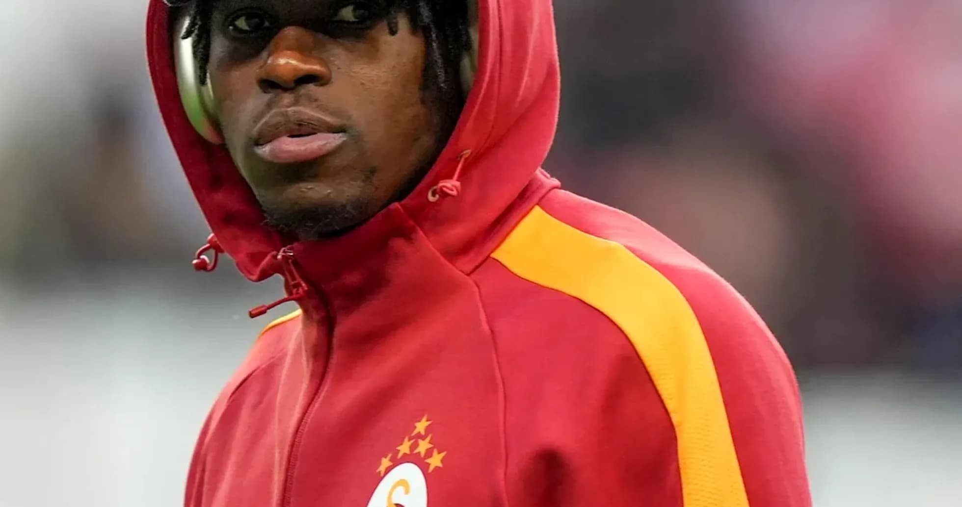 Player in red and yellow Galatasaray hoodie on sidelines Player in red and yellow Galatasaray hoodie on sidelines
