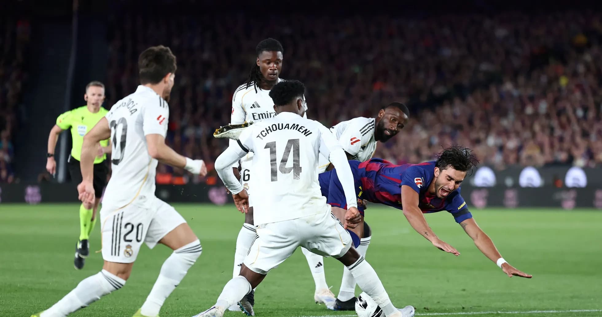 Barcelona player falling while tackled by Real Madrid defenders Barcelona player falling while tackled by Real Madrid defenders