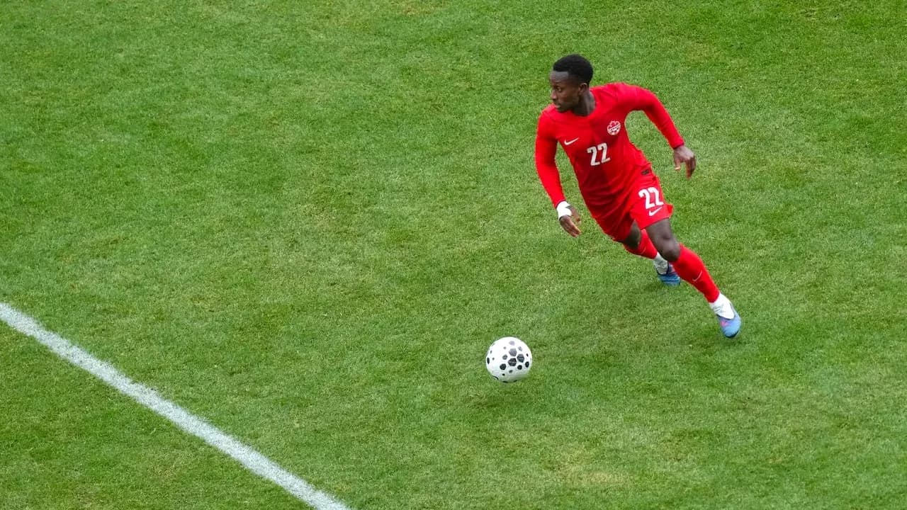 Player in red jersey dribbling ball on field Player in red jersey dribbling ball on field