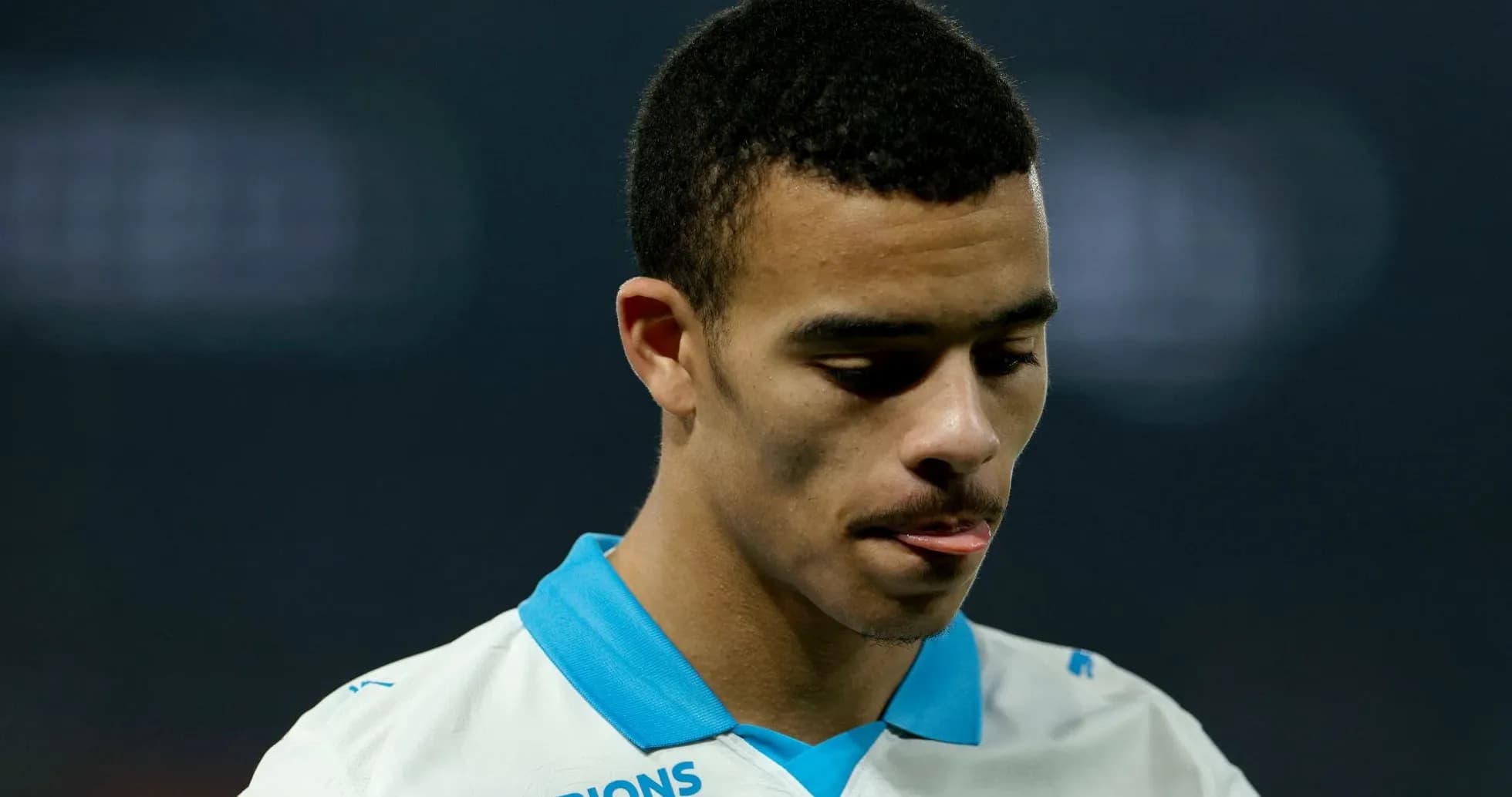 Player in white jersey looking down with focused expression Player in white jersey looking down with focused expression