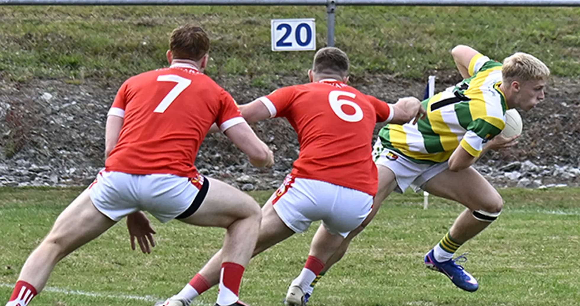Player in green and yellow evading two opponents Player in green and yellow evading two opponents