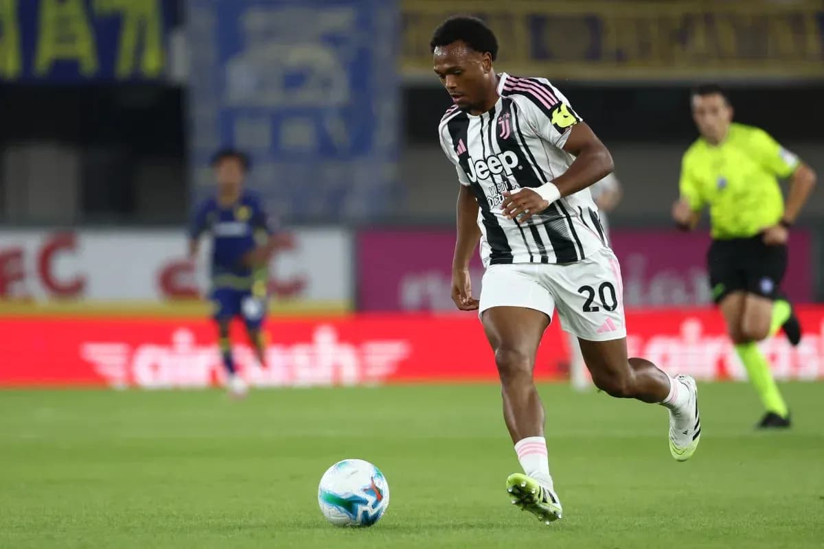 Player in Juventus kit dribbling the ball on field Player in Juventus kit dribbling the ball on field