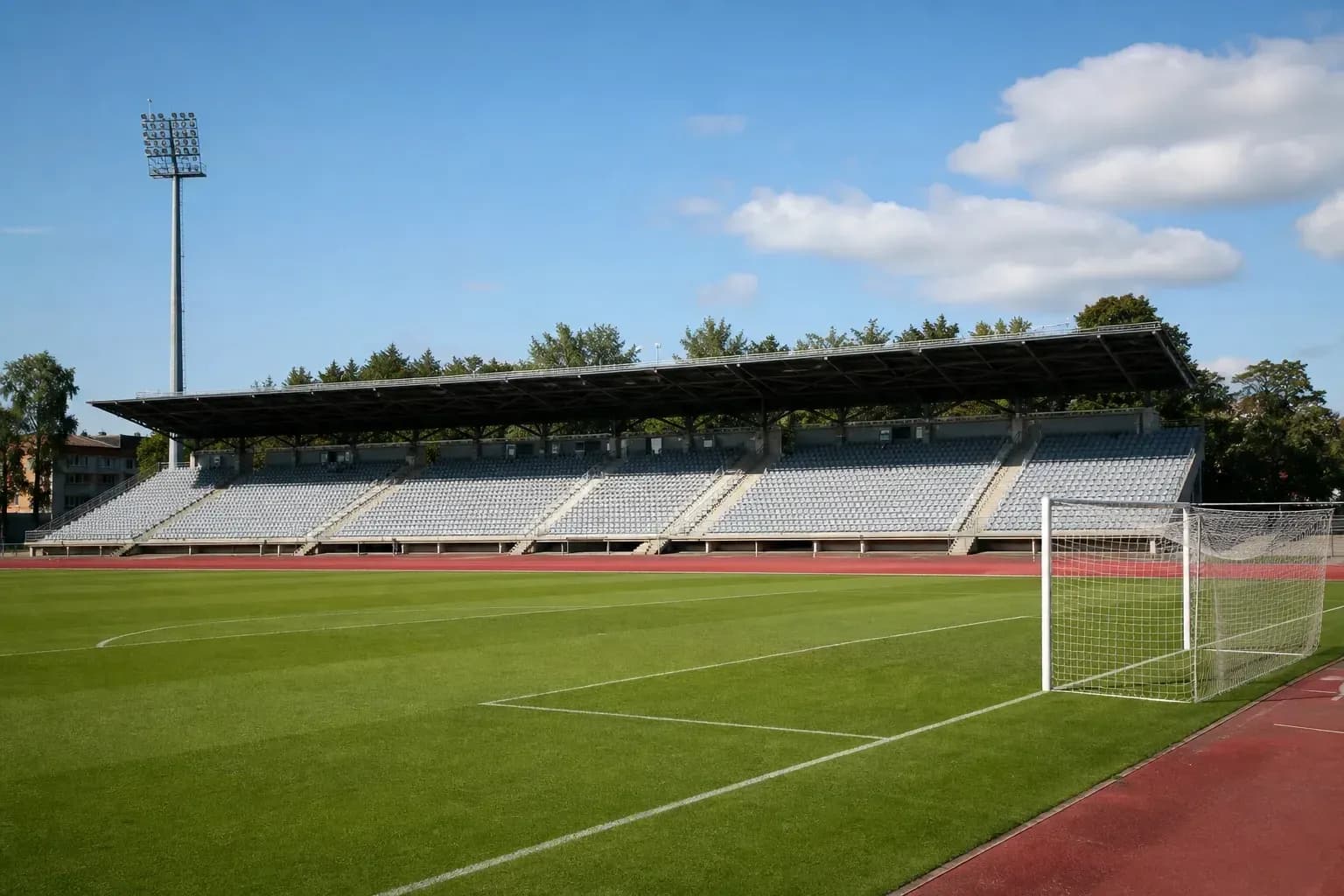 Empty football stadium with green pitch and goalpost Empty football stadium with green pitch and goalpost