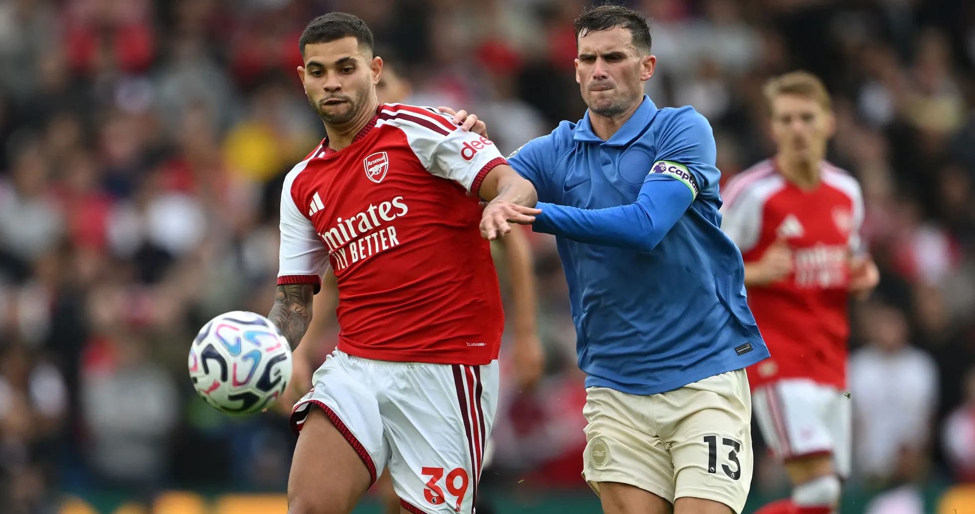 Arsenal player dribbling past opponent during match Arsenal player dribbling past opponent during match