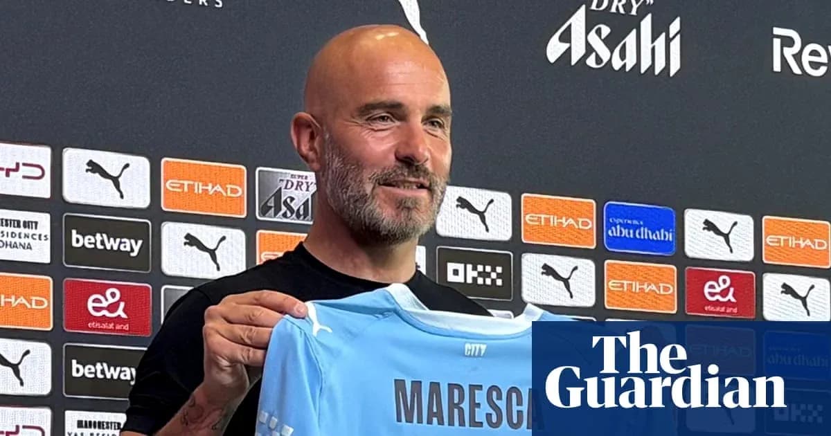 Coach holding Manchester City jersey at press conference Coach holding Manchester City jersey at press conference