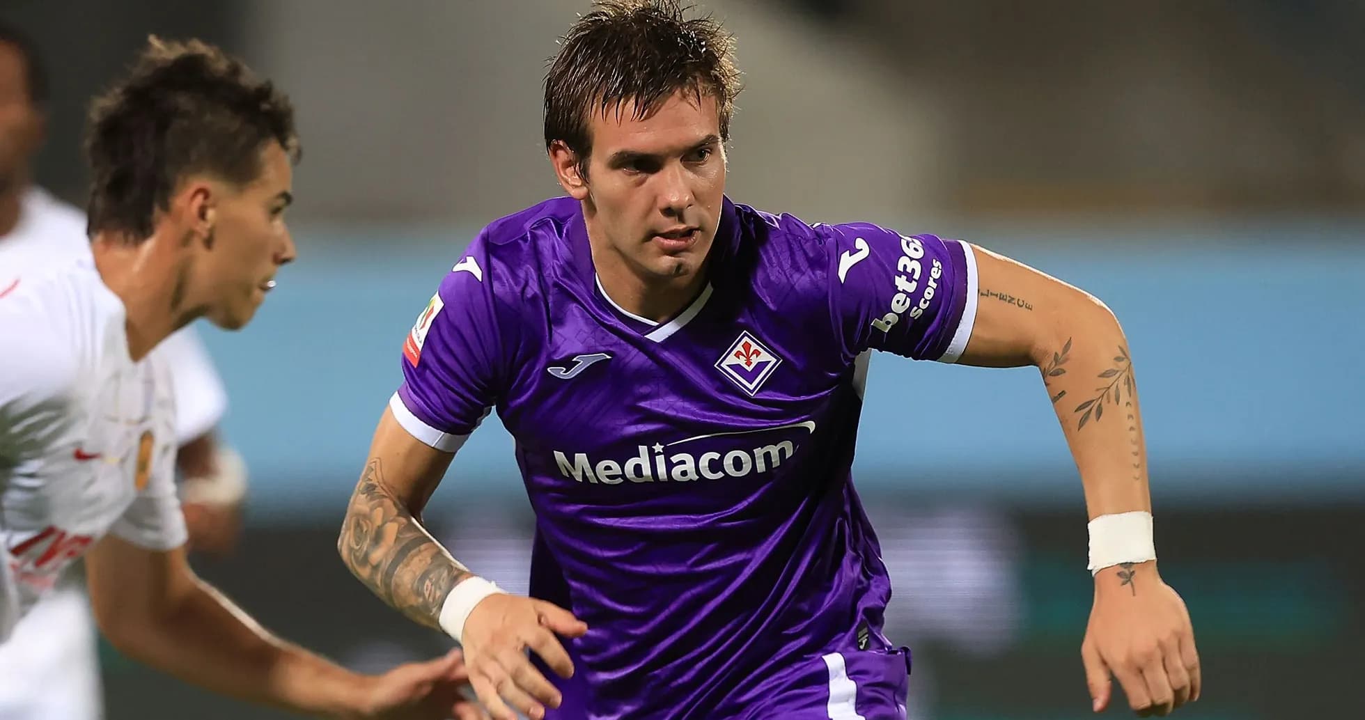 Player in purple kit sprinting during match Player in purple kit sprinting during match