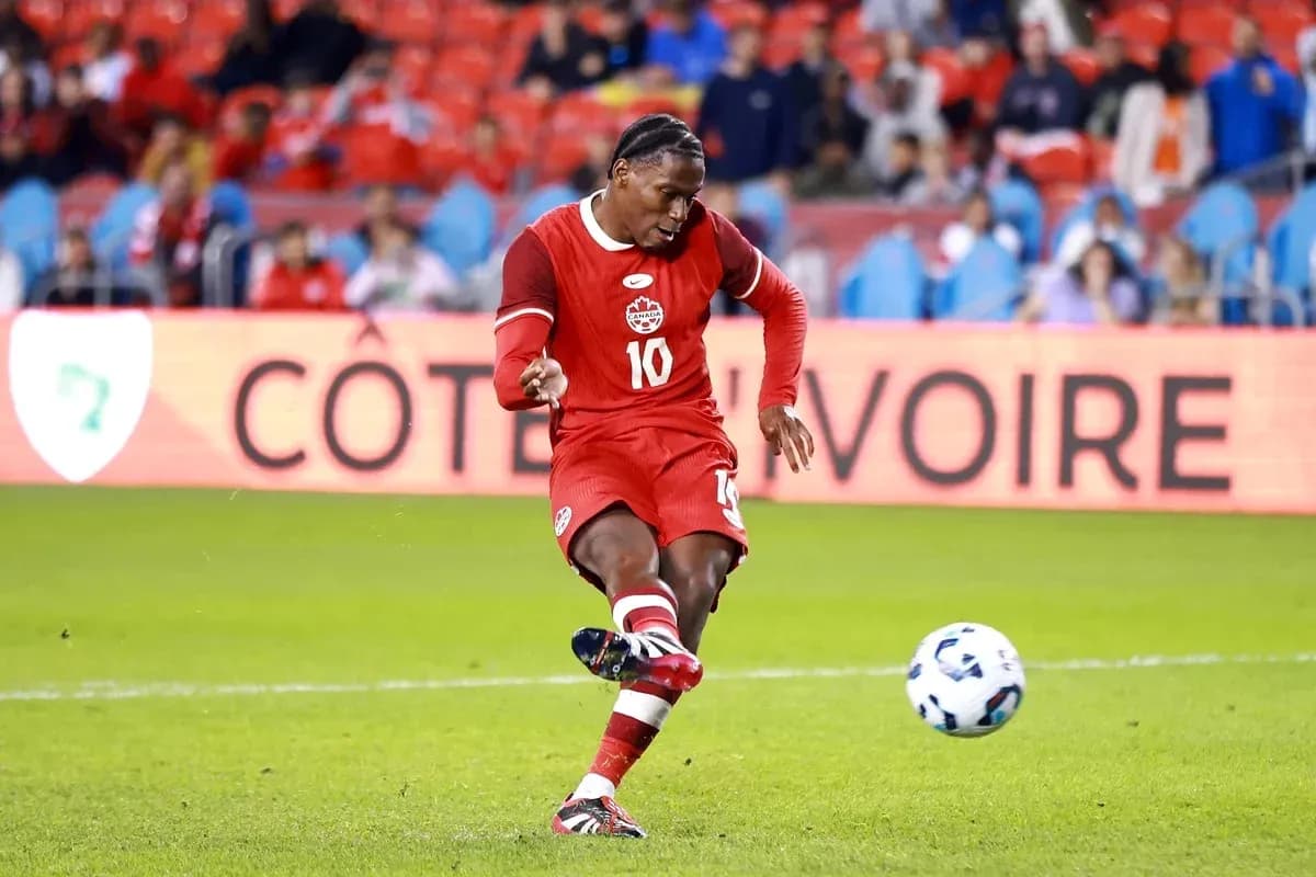 Player in red kit kicking soccer ball on field Player in red kit kicking soccer ball on field