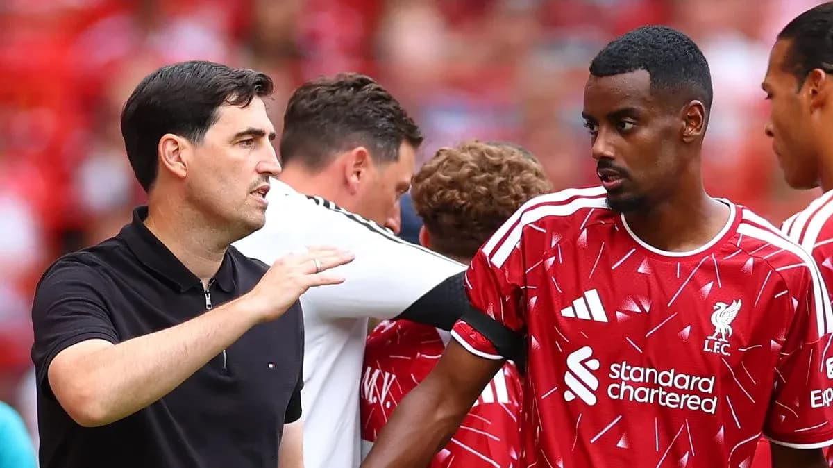 Coach discussing strategy with Liverpool player on pitch Coach discussing strategy with Liverpool player on pitch