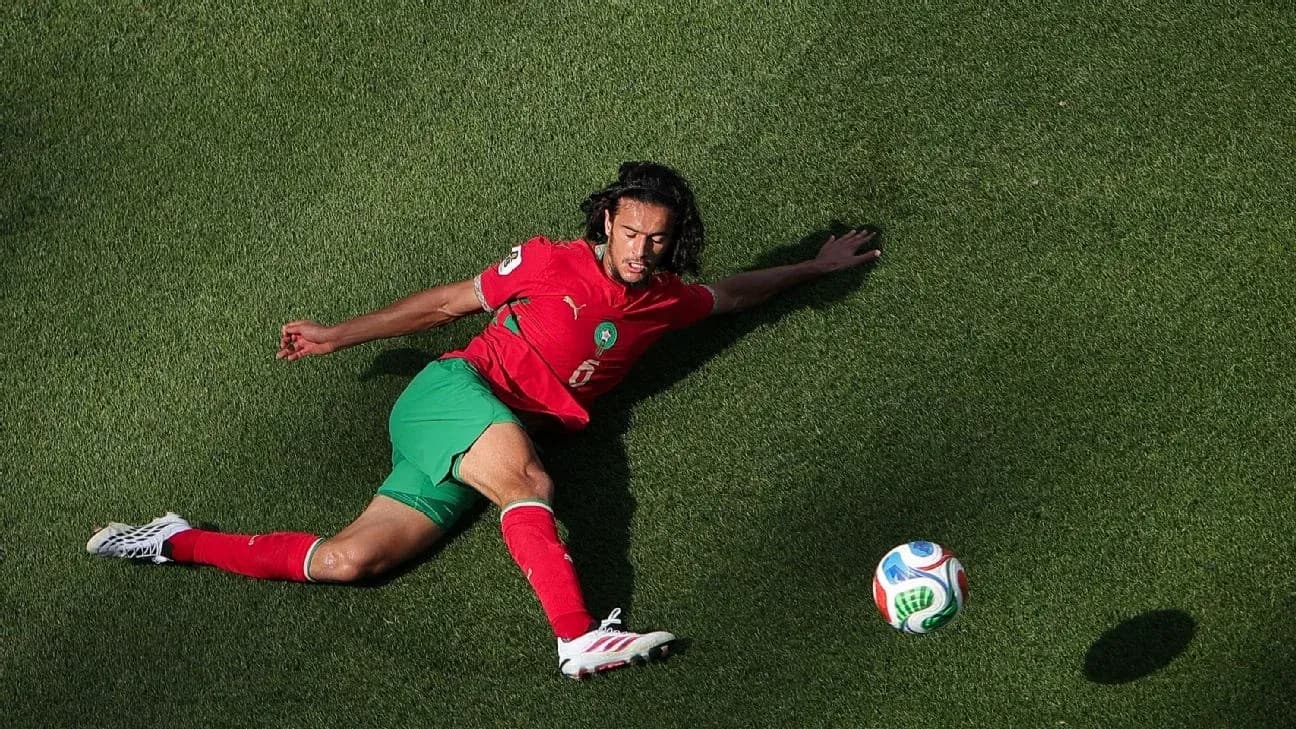 Player sliding on grass with soccer ball nearby Player sliding on grass with soccer ball nearby