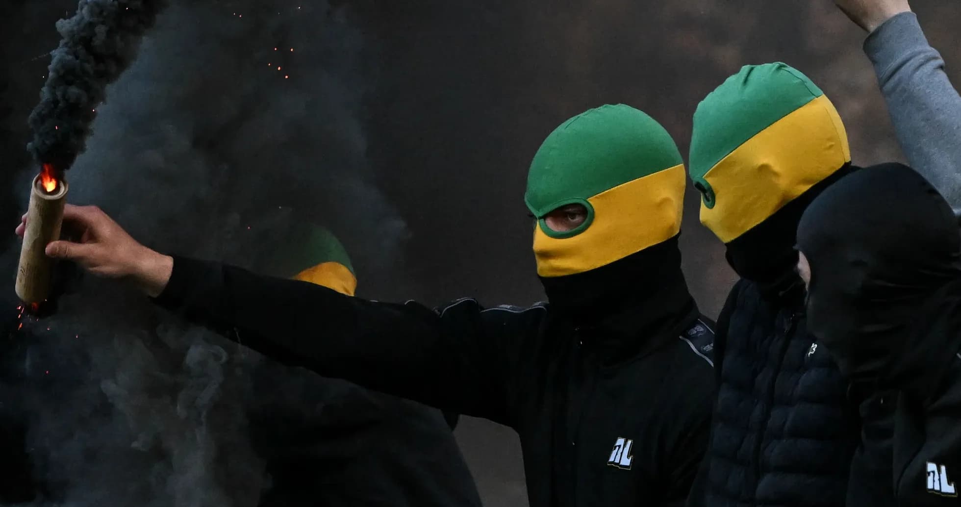 Masked individuals holding flares in smoke-filled area Masked individuals holding flares in smoke-filled area