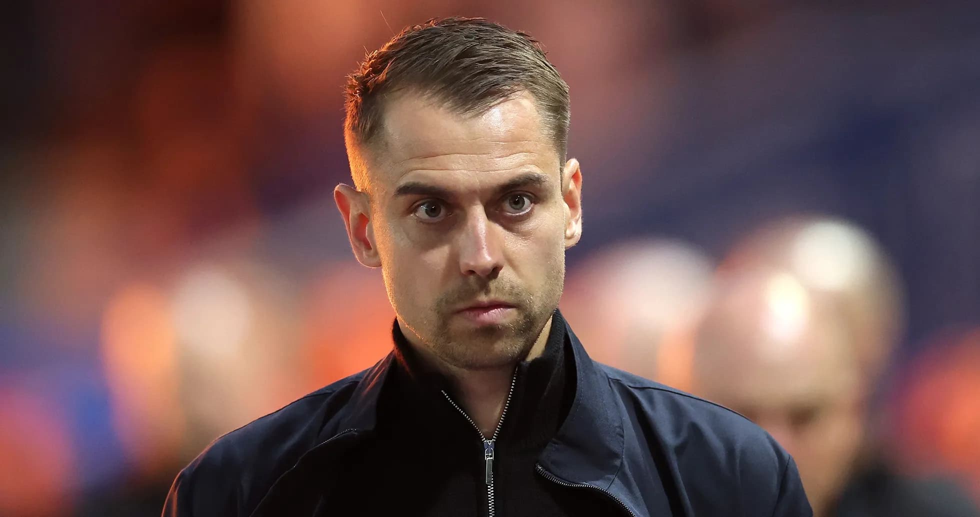Man in dark jacket walking on sports field Man in dark jacket walking on sports field