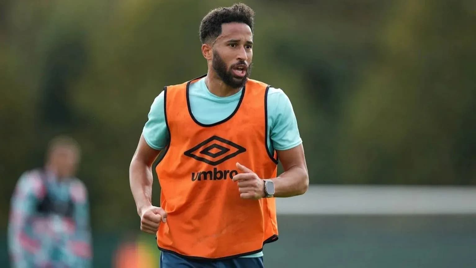 Player in orange training bib running on pitch Player in orange training bib running on pitch