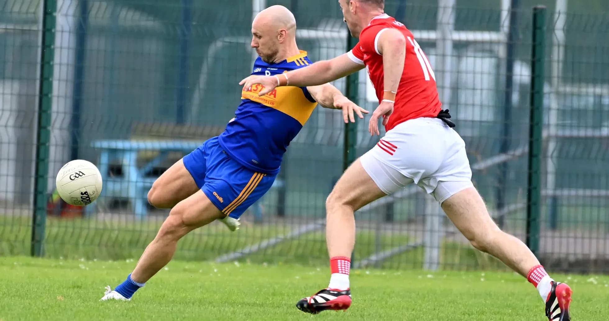 Player kicking the ball while being challenged Player kicking the ball while being challenged
