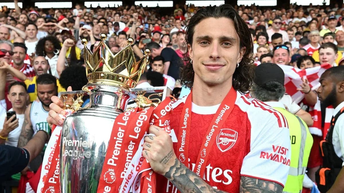 Player holding Premier League trophy with fans in background Player holding Premier League trophy with fans in background
