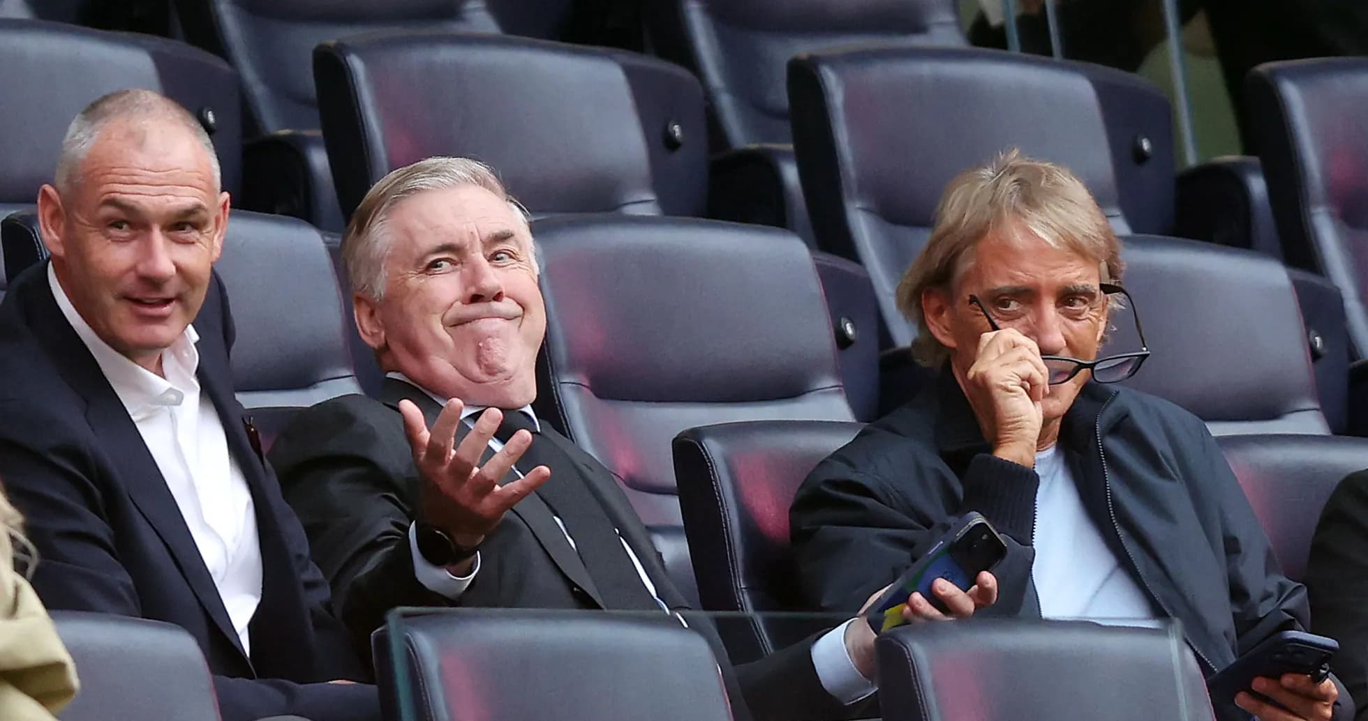 Three men seated in stadium watching event Three men seated in stadium watching event