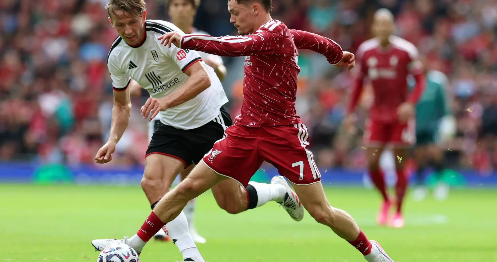 Liverpool player tackling Fulham opponent during match Liverpool player tackling Fulham opponent during match
